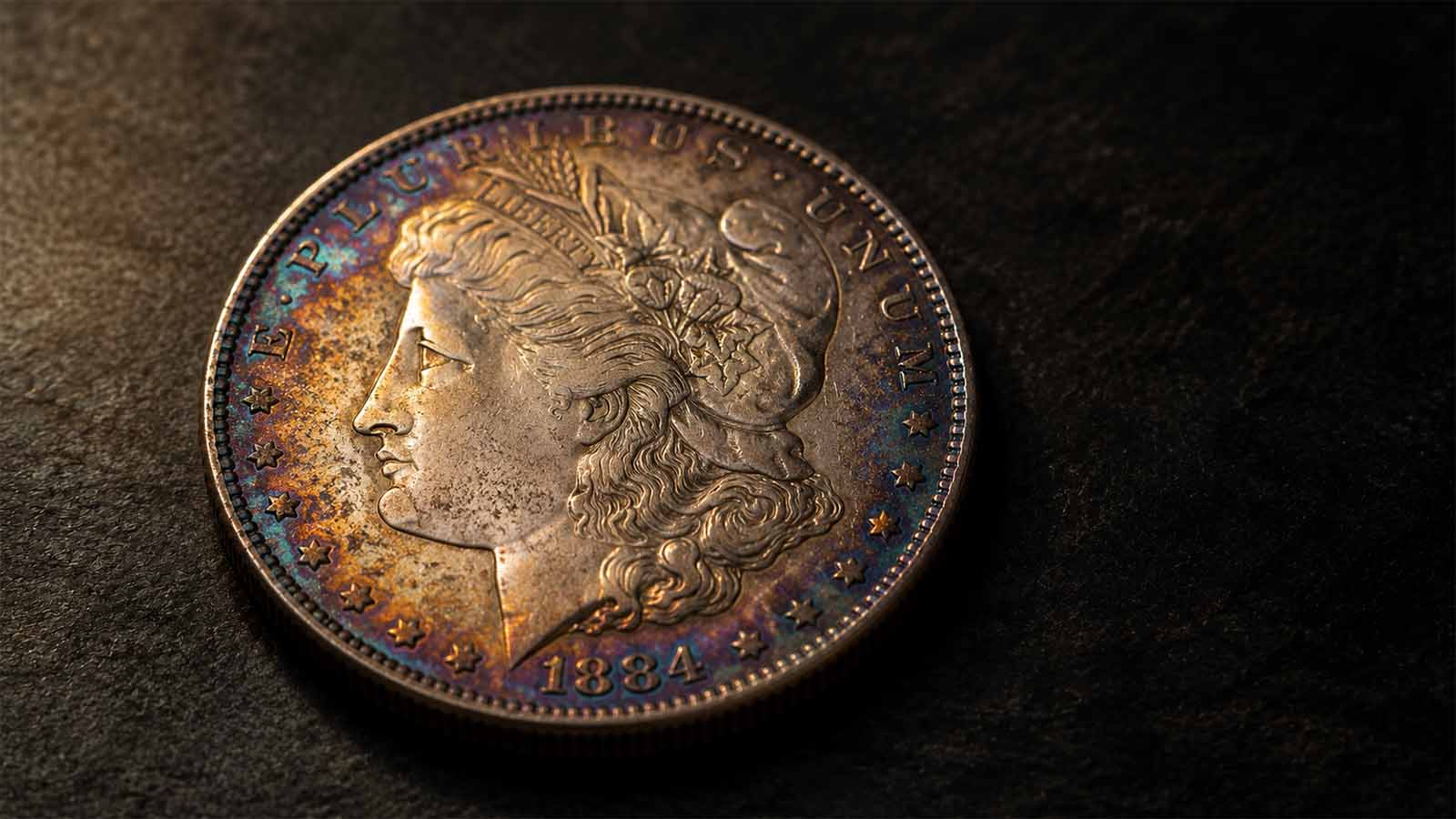 Macro close-up of a Morgan silver dollar with natural rainbow toning on a dark surface